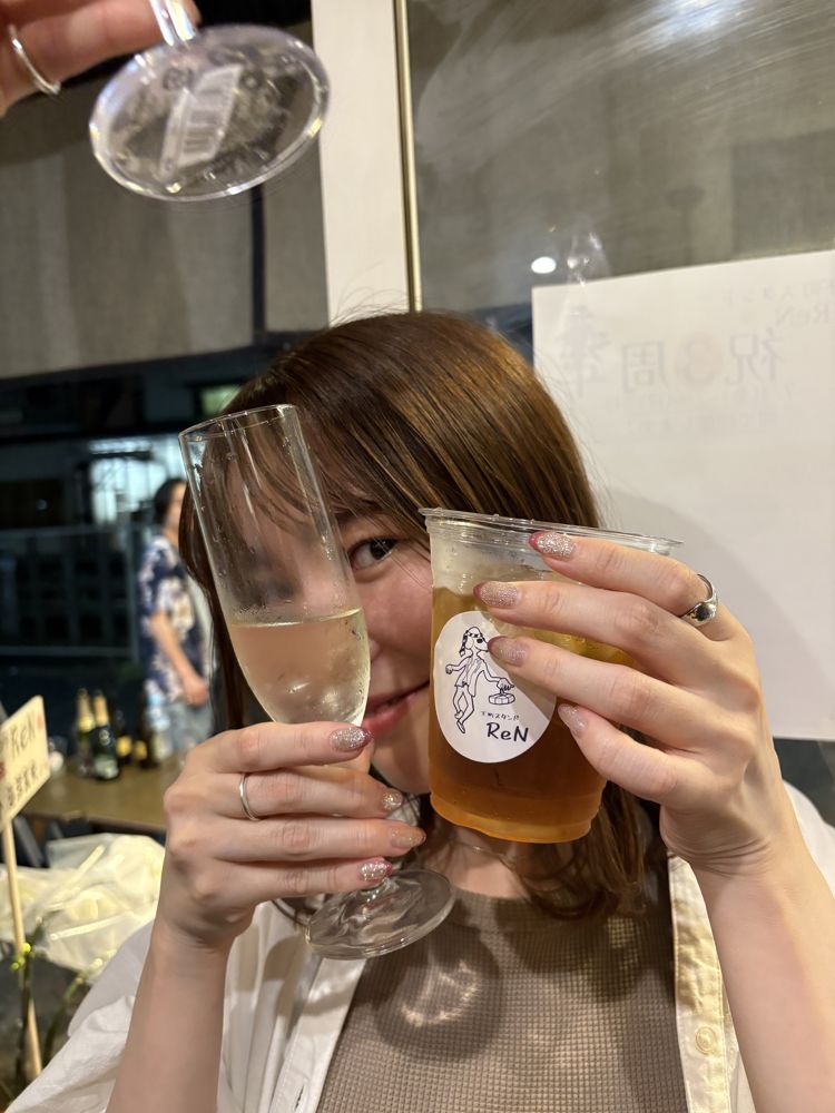 グラスとカップを両手に持って乾杯する女性